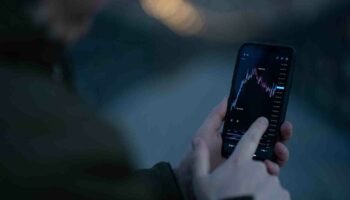 Businessman monitoring stock market data while trading online in mobile app React-Native-Framework